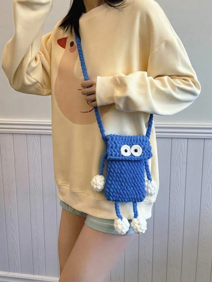 Handmade blue crochet monster sling pouch with googly eyes and pom-pom legs
