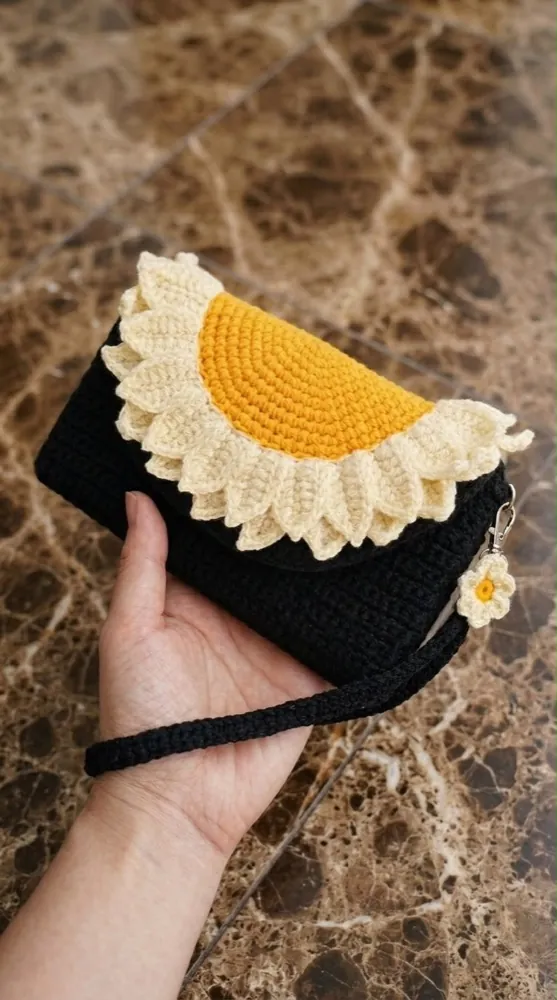 Handmade black crochet clutch with a cream and yellow sunflower flap and a wrist strap