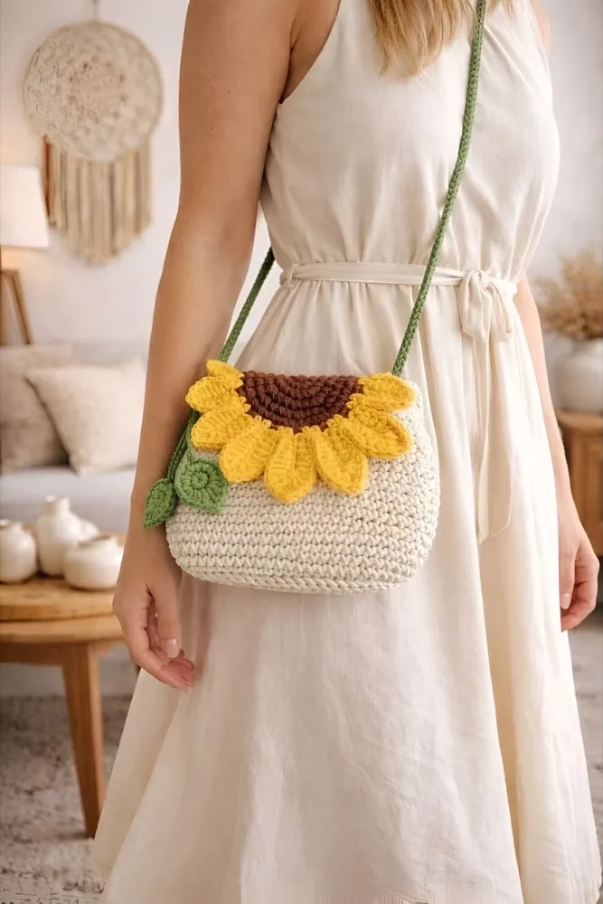 Handmade cream crochet sling bag with a big yellow sunflower, worn over a white dress