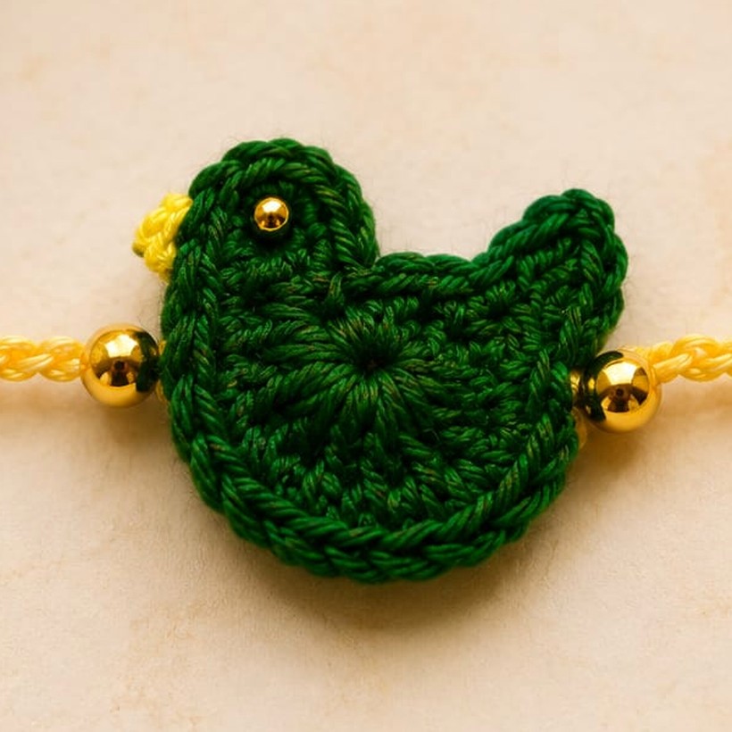 Handmade crochet green bird rakhi with gold beads on a yellow thread