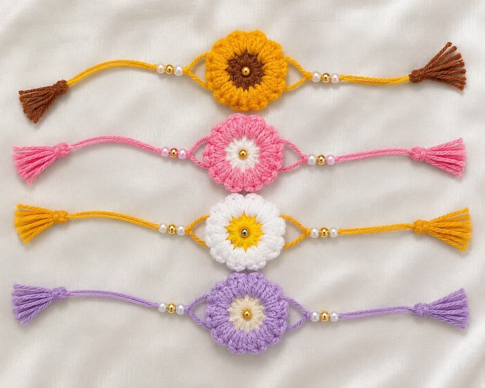 Four handmade crochet blossom rakhis in yellow, pink, white and lilac with tassels and beads