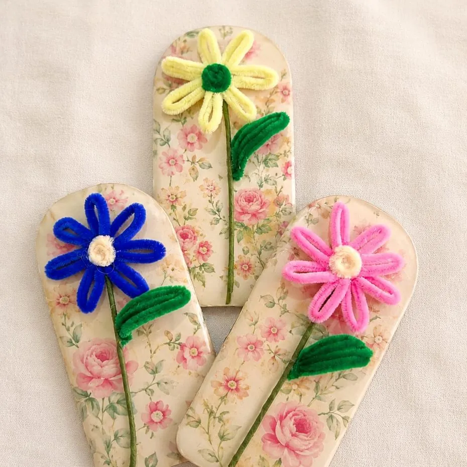 Handmade flower hair clips on floral-print bases in blue, yellow and pink