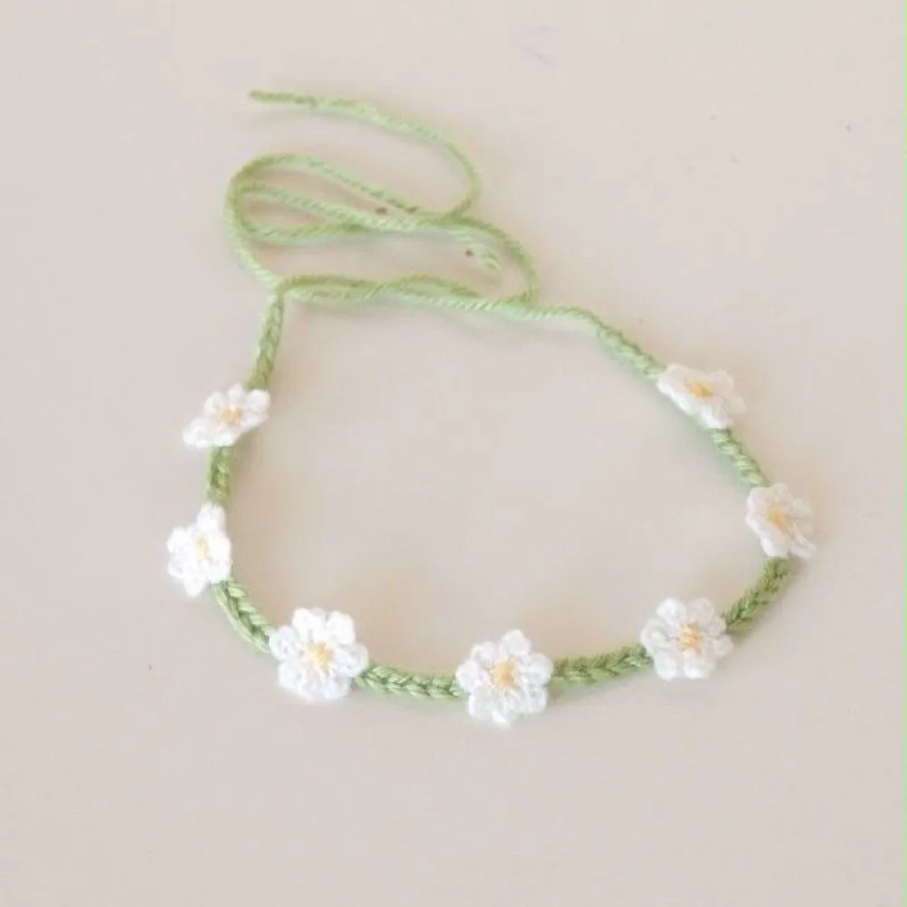 Handmade crochet daisy chain rakhi with white flowers on a green thread