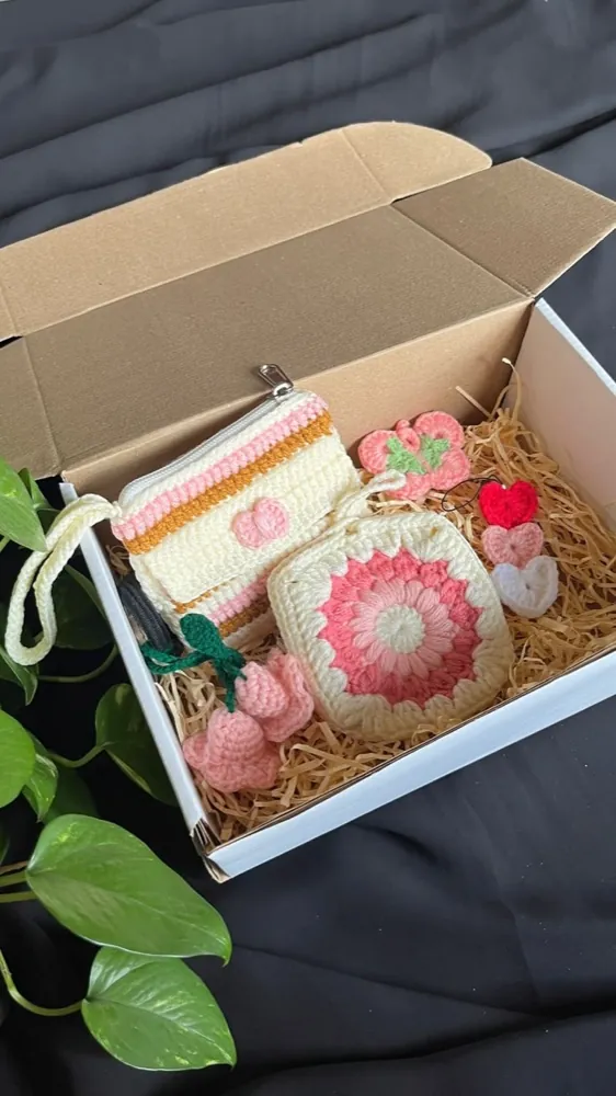 Handmade pink crochet gift box — striped zip pouch, flower granny square and heart and flower charms