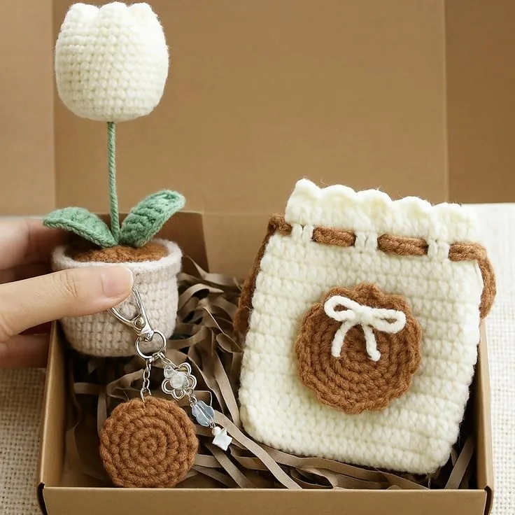 Handmade crochet gift box — white tulip in a pot, cream drawstring pouch with a brown bow patch, and a round keychain