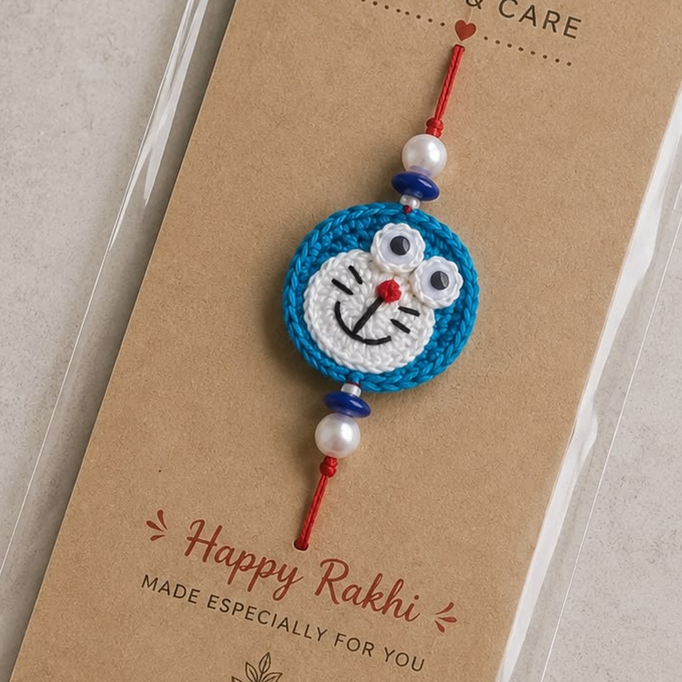 Handmade crochet Doraemon face rakhi with pearl and blue beads on a red thread