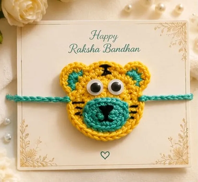 Handmade crochet tiger face rakhi in yellow and teal with googly eyes